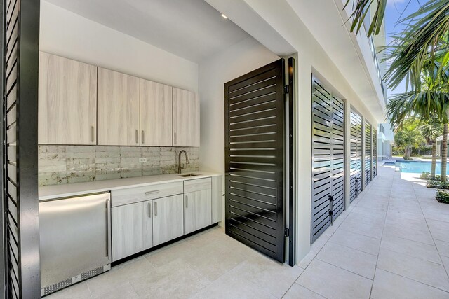 kitchen with backsplash, light brown cabinets, sink, and stainless steel refrigerator