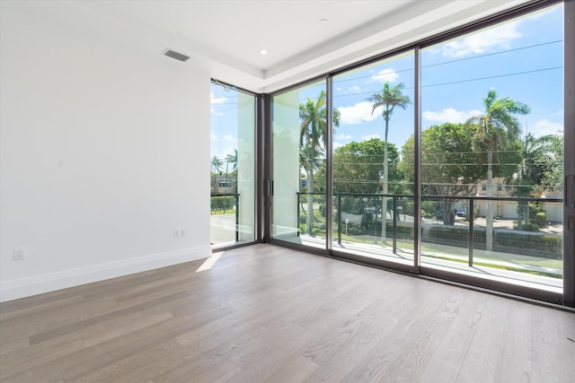 unfurnished room with floor to ceiling windows, plenty of natural light, and hardwood / wood-style floors