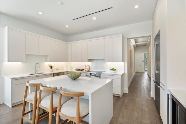 kitchen with a center island, sink, a breakfast bar area, and white cabinets