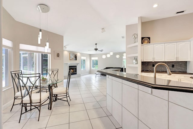 kitchen with hanging light fixtures, light tile flooring, white cabinetry, backsplash, and ceiling fan