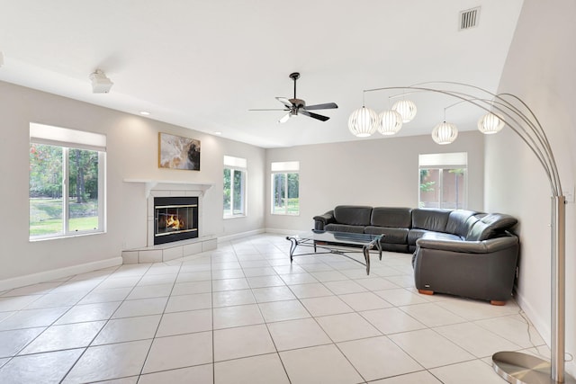 living room featuring ceiling fan, light tile floors, and a fireplace