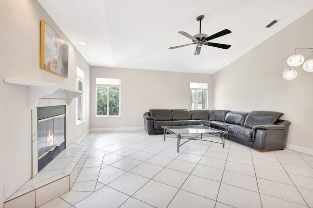 living room featuring vaulted ceiling, ceiling fan, light tile flooring, and a tiled fireplace