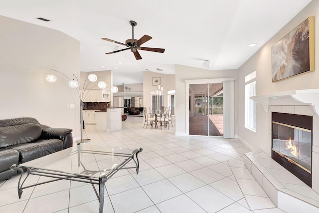 tiled living room featuring vaulted ceiling, ceiling fan, and a fireplace