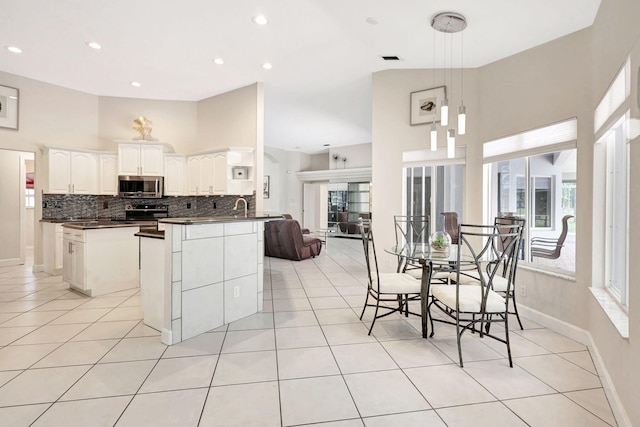 kitchen with decorative light fixtures, white cabinetry, appliances with stainless steel finishes, a kitchen island, and tasteful backsplash