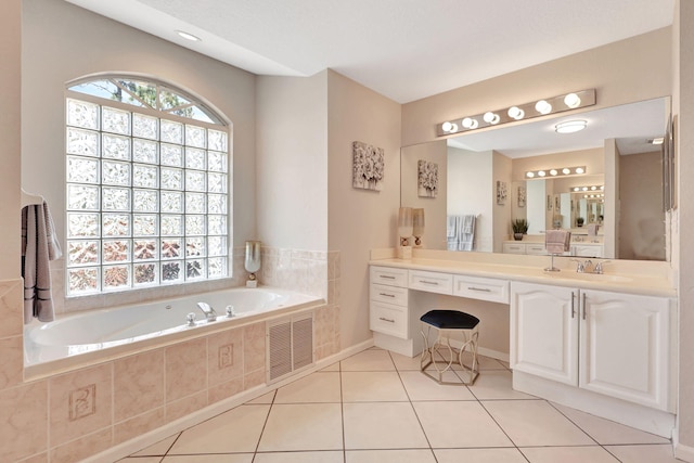 bathroom with tile flooring, vanity, and tiled bath