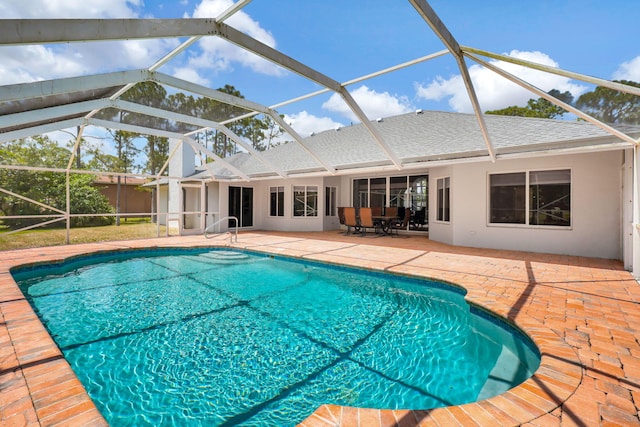 view of pool with glass enclosure and a patio area