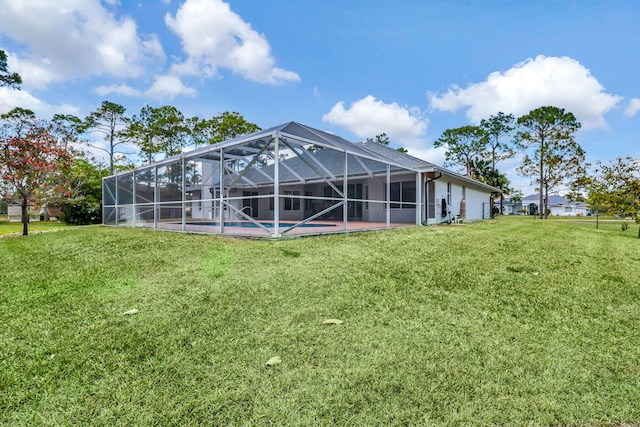 back of property with glass enclosure and a lawn