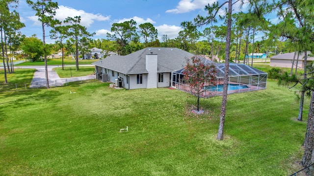 rear view of property with glass enclosure and a lawn