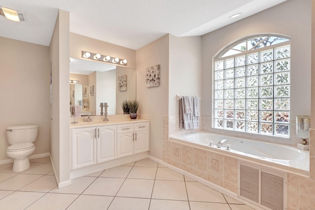 bathroom featuring tiled bath, vanity, tile flooring, toilet, and a textured ceiling