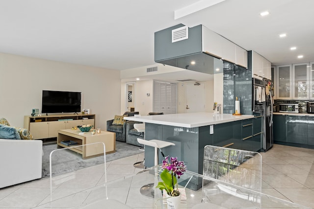 kitchen with light tile floors, double wall oven, white cabinets, and a breakfast bar area