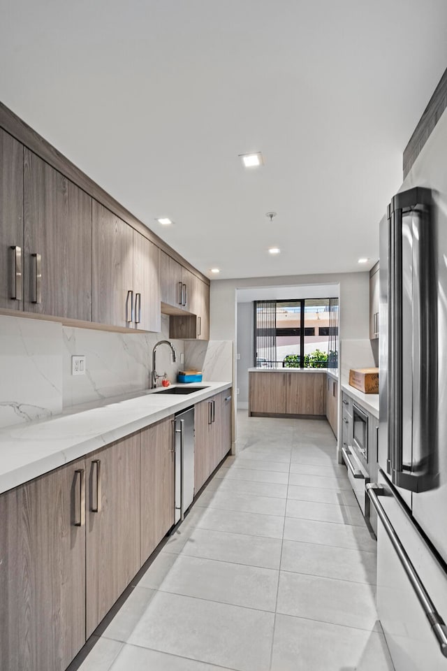 kitchen featuring light stone counters, appliances with stainless steel finishes, sink, tasteful backsplash, and light tile flooring