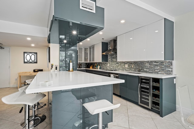 kitchen with a kitchen island, a breakfast bar area, tasteful backsplash, wall chimney exhaust hood, and light tile floors