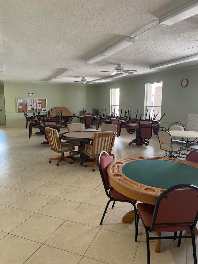 recreation room featuring a textured ceiling, ceiling fan, and light tile flooring