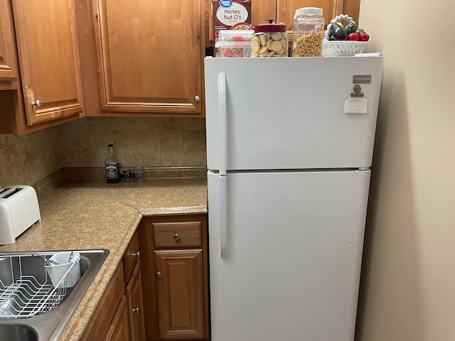 kitchen featuring white refrigerator and backsplash