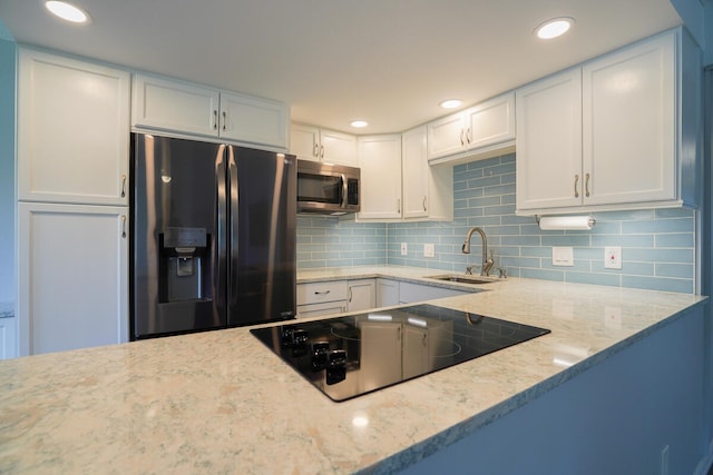 kitchen with light stone countertops, tasteful backsplash, sink, white cabinets, and appliances with stainless steel finishes