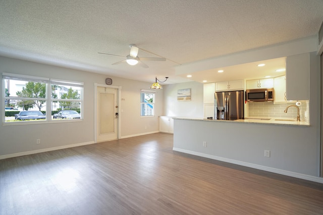 unfurnished living room with dark wood-type flooring, ceiling fan, and a textured ceiling