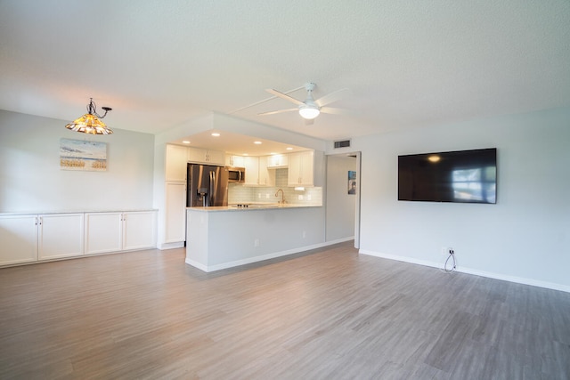 unfurnished living room featuring hardwood / wood-style floors, sink, and ceiling fan