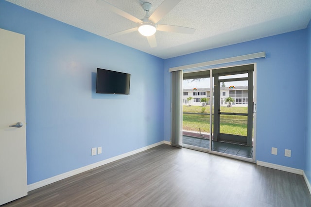 spare room with dark hardwood / wood-style floors, ceiling fan, and a textured ceiling