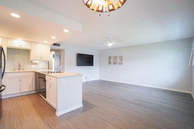 kitchen with kitchen peninsula, backsplash, ceiling fan, hardwood / wood-style floors, and white cabinetry