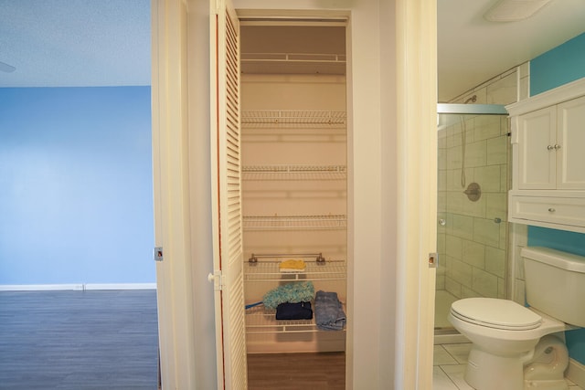 bathroom with walk in shower, a textured ceiling, toilet, and hardwood / wood-style floors