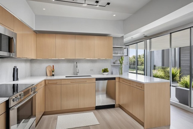 66 Capri B, Delray Beach, FL 33484 - kitchen featuring appliances with stainless steel finishes, a sink, a peninsula, open shelves, and light wood-style floors