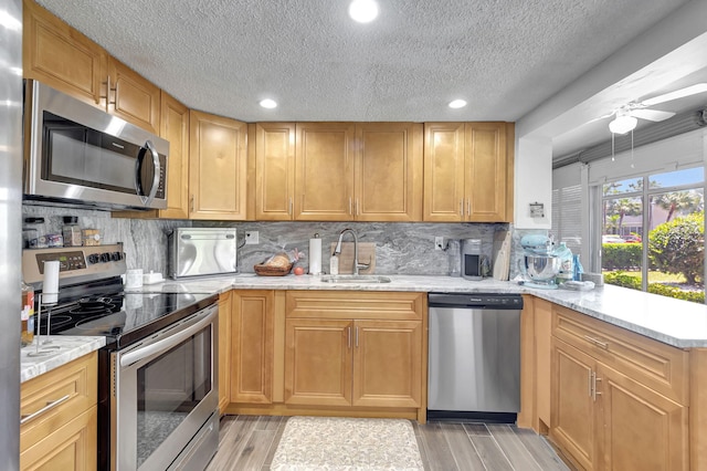 66 Capri B, Delray Beach, FL 33484 - kitchen featuring appliances with stainless steel finishes, a sink, a textured ceiling, decorative backsplash, and light wood finished floors