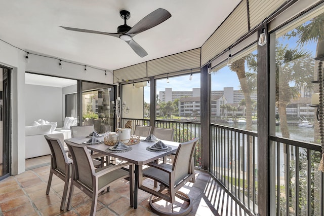 sunroom / solarium featuring ceiling fan and a water view