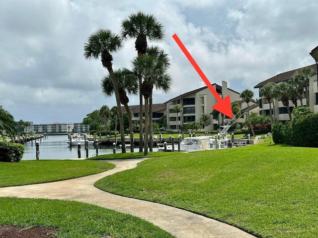 view of home's community featuring a yard, a water view, and a boat dock