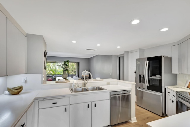 kitchen with sink, stainless steel appliances, and light hardwood / wood-style floors