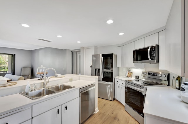 kitchen featuring appliances with stainless steel finishes, sink, light hardwood / wood-style floors, and white cabinets