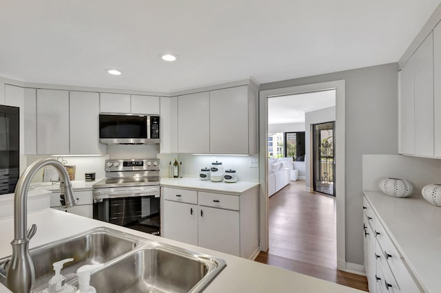 kitchen with appliances with stainless steel finishes, dark wood-type flooring, white cabinetry, and sink