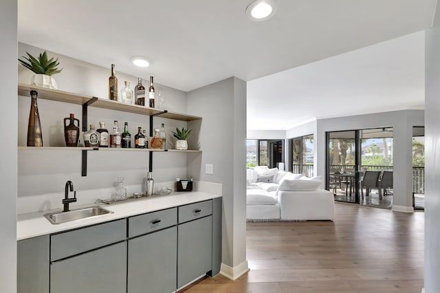 bar featuring sink, hardwood / wood-style flooring, and gray cabinetry