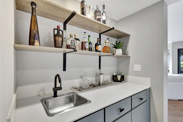 bar with hardwood / wood-style floors, sink, and gray cabinets