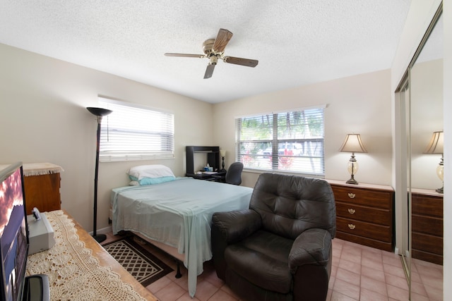 bedroom featuring a closet, ceiling fan, a textured ceiling, and light tile flooring