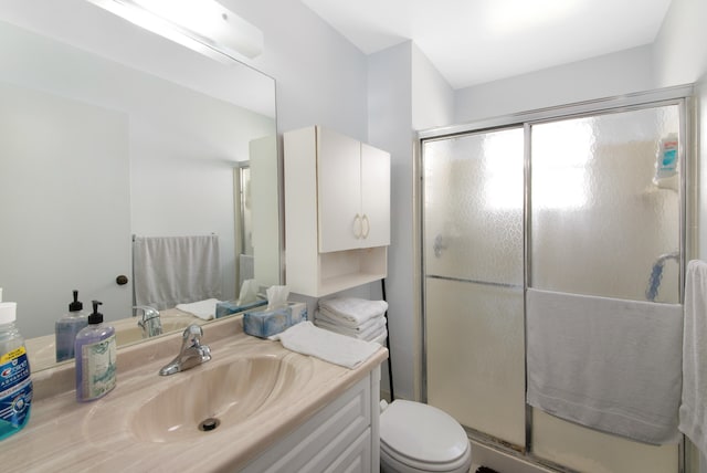 bathroom featuring a shower with door, toilet, and vanity