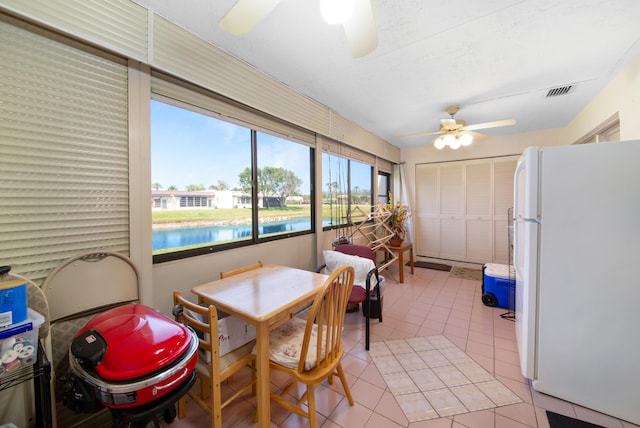 sunroom / solarium with ceiling fan and a water view