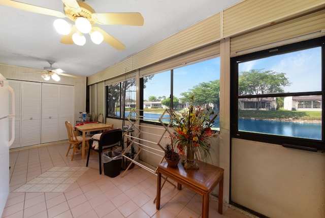 sunroom featuring ceiling fan and a water view