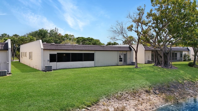 back of house with central AC unit and a lawn