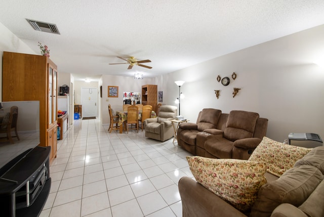 living room with ceiling fan, a textured ceiling, and light tile flooring