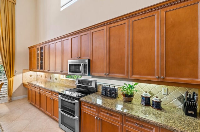 kitchen with light tile flooring, tasteful backsplash, stainless steel appliances, and stone counters