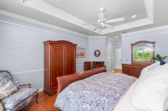 bedroom featuring ornamental molding, dark hardwood / wood-style floors, ceiling fan, and a raised ceiling