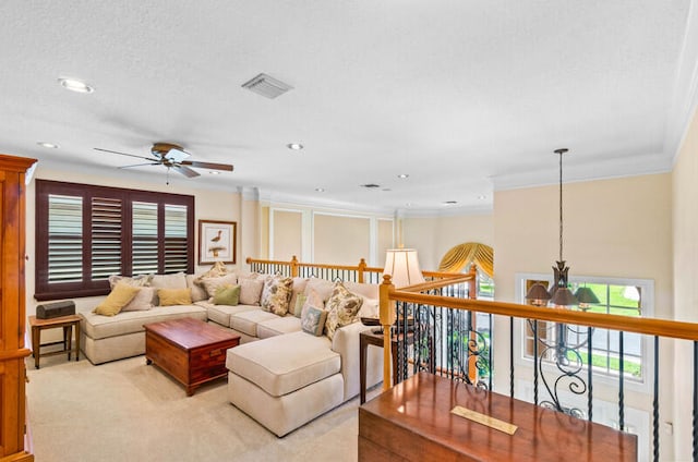 living room with ceiling fan, crown molding, carpet flooring, and a textured ceiling