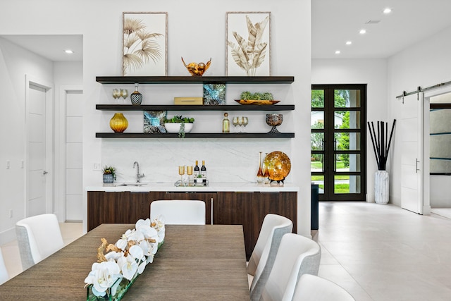 dining area with a barn door, french doors, and sink