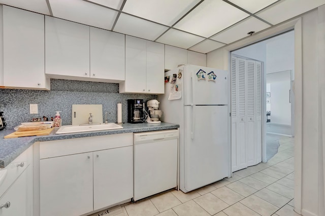 kitchen with white cabinets, white appliances, sink, light tile floors, and tasteful backsplash