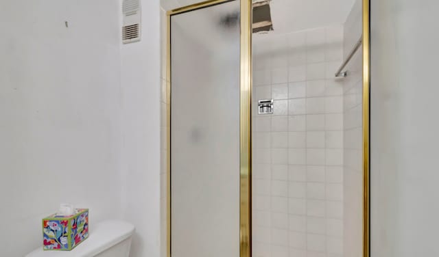 bathroom featuring a shower with door and toilet