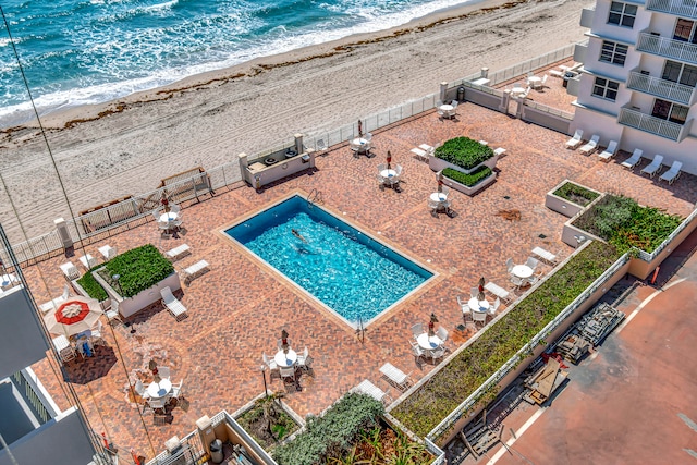 view of pool featuring a water view and a beach view