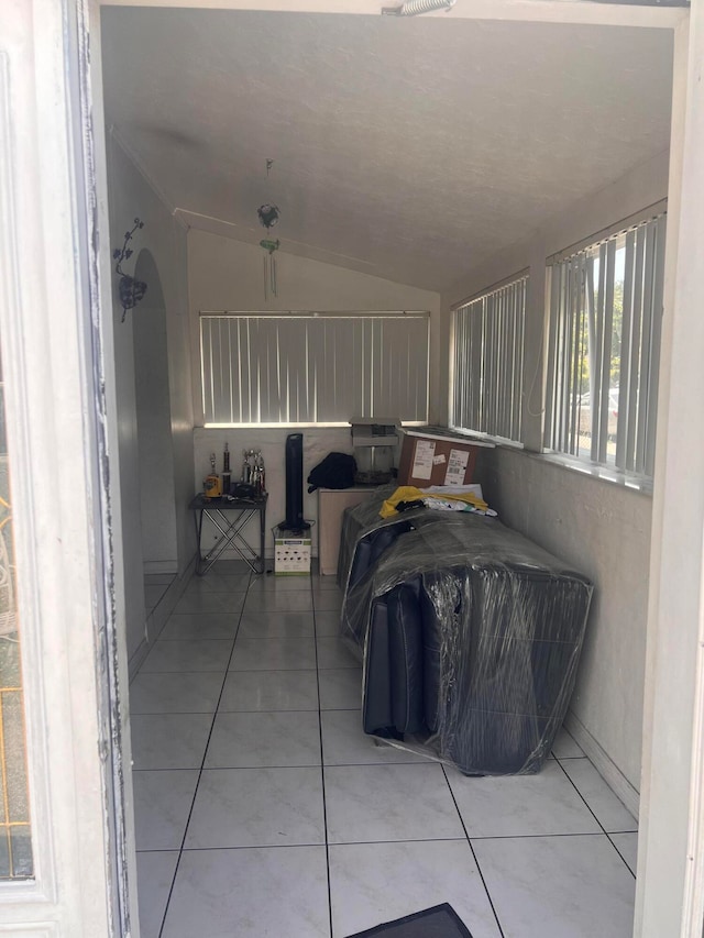 bedroom with light tile flooring and lofted ceiling