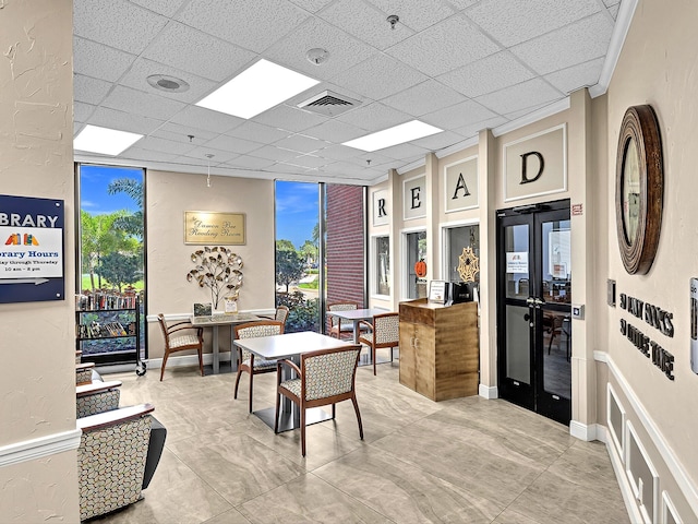 tiled dining room with a drop ceiling, french doors, and expansive windows