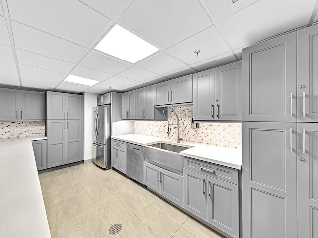 kitchen featuring tasteful backsplash, light tile floors, a paneled ceiling, and appliances with stainless steel finishes