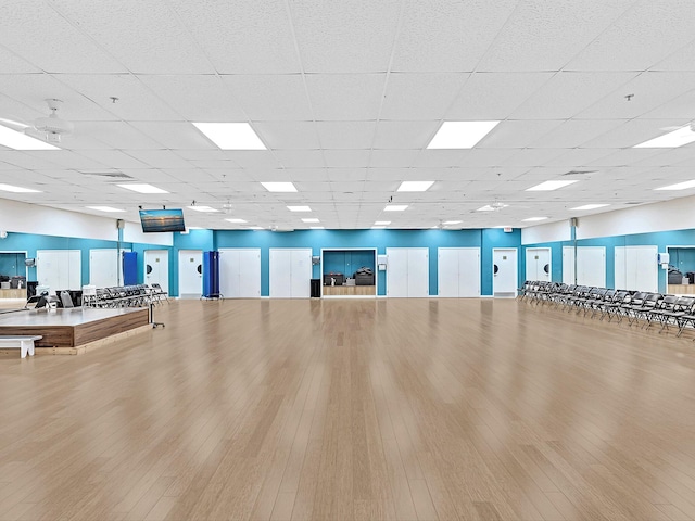 workout area featuring wood-type flooring and a drop ceiling